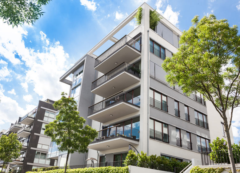 Außensicht von Wohngebäude mit Balkon und Grünanlagen
